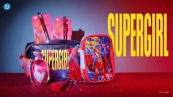 Kit de maquiagem Supergirl da Miss Frandy Kit de maquiagem e acessórios “Supergirl” da Miss Frandy, com necessaire rosa e produtos sobre fundo vermelho e azul.