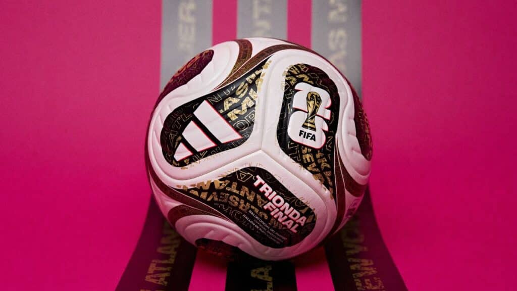 Bola oficial Adidas Trionda Final da Copa do Mundo FIFA 2026 em destaque no fundo rosa