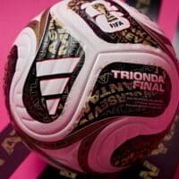 Bola oficial Adidas Trionda Final da Copa do Mundo FIFA 2026, com inscrição e logotipos, em fundo rosa