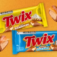 Embalagens de Twix Banoffee e Twix Cocada sobre fundo laranja, com cones de biscoito de sobremesa.