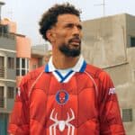 Vozinha, goleiro do Cabo Verde, em uniforme vermelho do Homem-Aranha em cena ao ar livre durante campanha da Sony Pictures.
