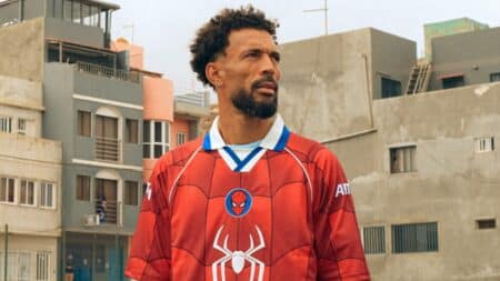 Vozinha, goleiro do Cabo Verde, em uniforme vermelho do Homem-Aranha em cena ao ar livre durante campanha da Sony Pictures.