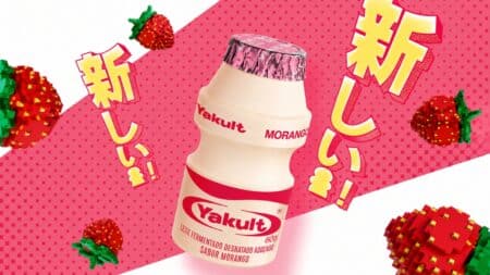 Yakult Morango – leite fermentado sabor morango Embalagem do Yakult Morango, leite fermentado sabor morango, sobre fundo rosa com morangos e escrita japonesa
