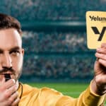 Árbitro em estádio segurando cartão amarelo com a marca Yelum