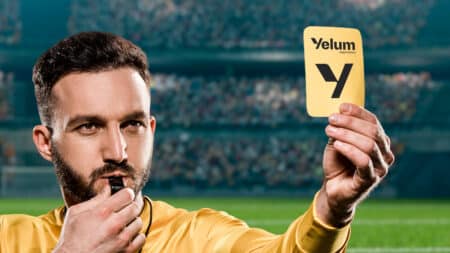 Árbitro em estádio segurando cartão amarelo com a marca Yelum