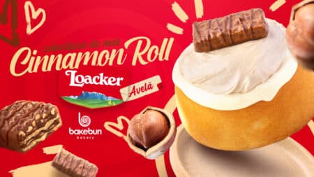 Cinnamon Roll Loacker exclusivo Bakebun Cinnamon roll Loacker da Bakebun com cobertura cremosa e pedaços de chocolate ao fundo vermelho, em promoção.