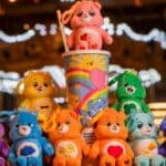 Copo surpresa da Cacau Show com personagens dos Ursinhos Carinhosos ao lado de pelúcias coloridas