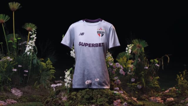 Camiseta do São Paulo feminina branca em fundo de jardim com flores, destaque para escudo e patrocinador no peito.