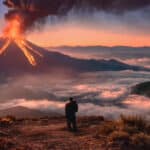 Campanha global do Burger King com chama e fumaça saindo de um vulcão ao pôr do sol, com pessoa em uma trilha na paisagem.