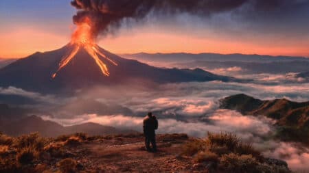 Campanha do Burger King: poder do fogo em cena com vulcão Campanha global do Burger King com chama e fumaça saindo de um vulcão ao pôr do sol, com pessoa em uma trilha na paisagem.