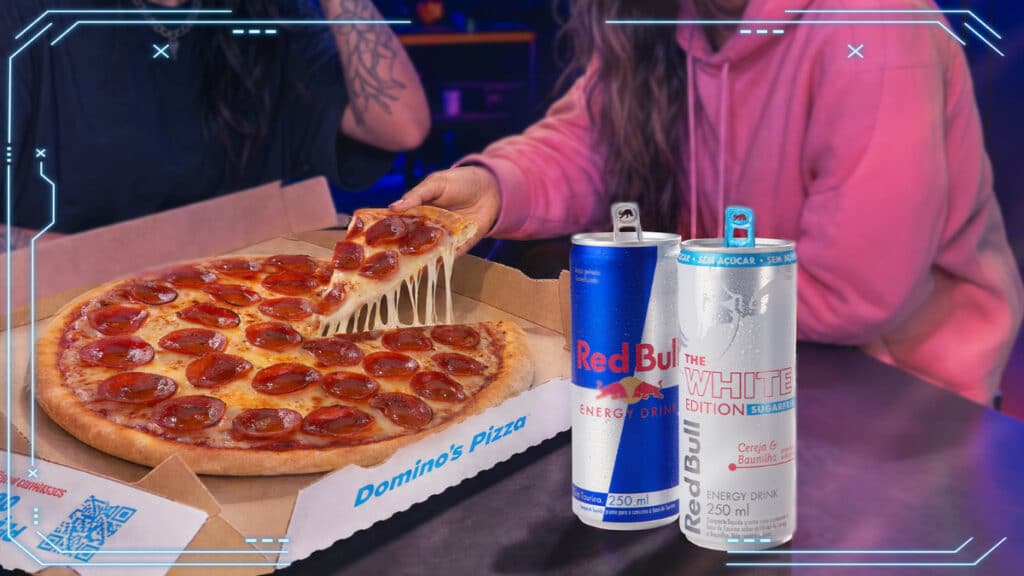 Domino’s e Red Bull: pizza e latas promocionais Mesa com pizza da Domino’s e latas de Red Bull, em parceria promocional.