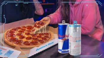Domino’s e Red Bull: pizza e latas promocionais Mesa com pizza da Domino’s e latas de Red Bull, em parceria promocional.