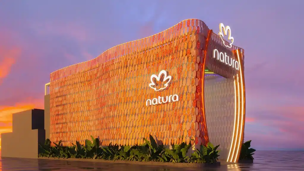 Estande da Natura no Rock in Rio 2026, com fachada em estrutura laranja e letreiro Natura ao pôr do sol.