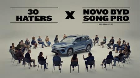 Campanha BYD “30 Haters” e novo Song Pro Flex Campanha BYD “30 Haters” com pessoas em círculo ao redor de um carro híbrido Song Pro Flex em imagem promocional.