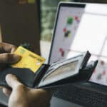 Pessoa paga com cartão de crédito enquanto usa notebook, cenário de golpes digitais e perdas financeiras da Geração Z