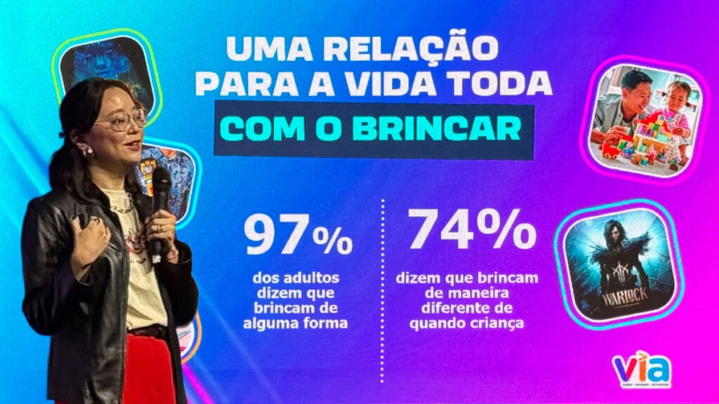Palestrante em evento Hasbro, com slide mostrando 97% dos adultos brincam e 74% brincam de maneira diferente na infância.