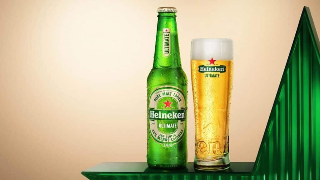 Heineken Ultimate em garrafa e copo para o Rock in Rio Brasil 2026 Garrafa verde Heineken Ultimate e copo com cerveja dourada sobre fundo verde, em imagem promocional do Rock in Rio.