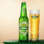 Garrafa verde Heineken Ultimate e copo com cerveja dourada sobre fundo verde, em imagem promocional do Rock in Rio.