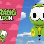 Balão de ar quente do Horácio, personagem verde com roupa amarela, em voo; lado a lado com arte promocional “Horácio Balloon”.