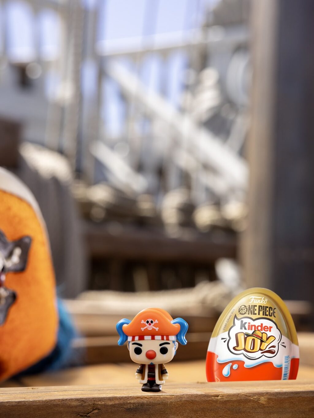 Miniatura de personagem estilo One Piece e ovo Kinder Joy colecionável na mesa, em ambiente externo.