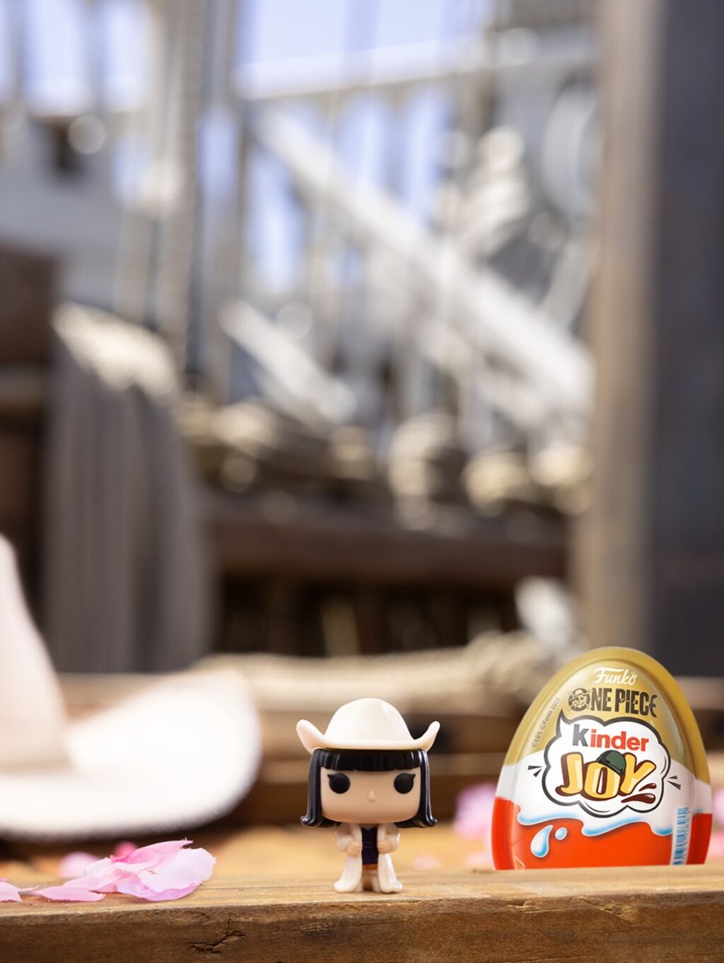 Boneco colecionável de One Piece com embalagem Kinder Joy sobre mesa de madeira, em cenário de fundo desfocado.