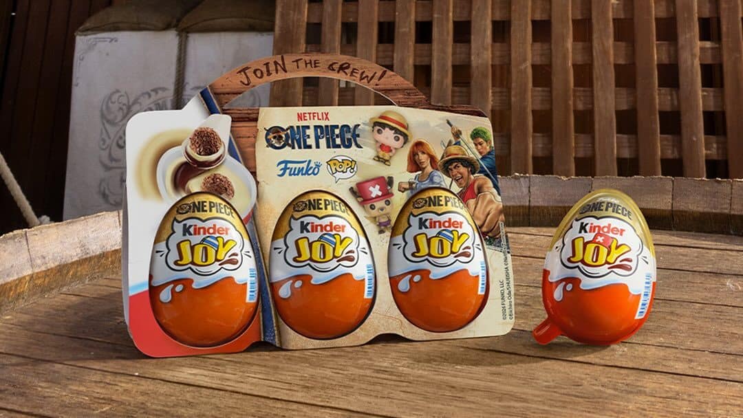 Embalagens de ovos Kinder Joy One Piece na mesa, com chocolates em formato de ovo e personagens ao fundo