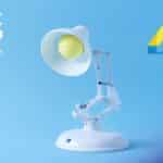 Luminária interativa Luxo Jr. branca com olhos amarelos em fundo azul, com logotipos “D23” e “Pixar 40 Years”.