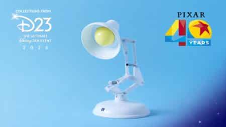 Luminária interativa Luxo Jr. 40 anos Pixar (D23) Luminária interativa Luxo Jr. branca com olhos amarelos em fundo azul, com logotipos “D23” e “Pixar 40 Years”.