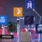 Coleção MINISO Star Wars com figuras em caixas e displays no fundo roxo, incluindo quadros com personagens e símbolos.