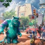 Personagem Sulley de Monstros S.A. em área temática da Disney, com crianças e cenários inspirados em Monstropolis.