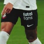 Jogador em campo com shorts pretos da Nike e logo “fatal fans”, em contexto de parceria com o Corinthians.