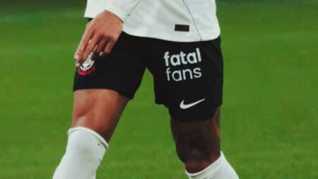 Jogador em campo com shorts pretos da Nike e logo “fatal fans”, em contexto de parceria com o Corinthians.
