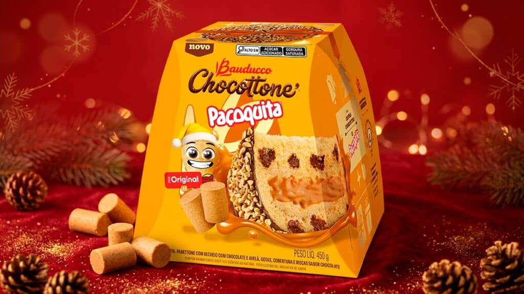 Chocottone Paçoquita Bauducco para o Natal 2026 Chocottone Paçoquita Bauducco em embalagem amarela sobre fundo vermelho de Natal, com farofa e biscoitos ao redor.