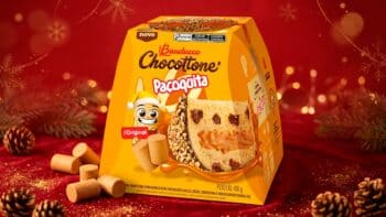 Chocottone Paçoquita Bauducco para o Natal 2026 Chocottone Paçoquita Bauducco em embalagem amarela sobre fundo vermelho de Natal, com farofa e biscoitos ao redor.