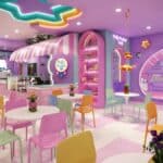 Ambiente interno do café temático da Polly Pocket no Brasil, com decoração rosa, mesas coloridas e área de balcão