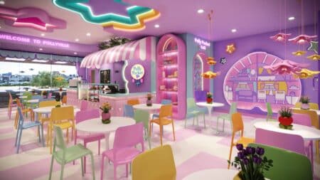 Ambiente interno do café temático da Polly Pocket no Brasil, com decoração rosa, mesas coloridas e área de balcão