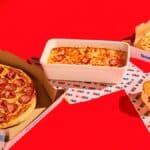 Promoção da Domino’s com pizzas e lasanha em caixas, fundo vermelho