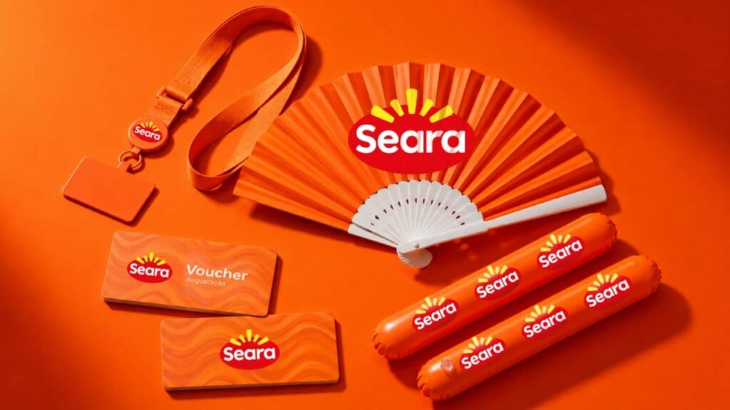Brindes da marca Seara para o Rock in Rio 2026: leque, voucher e itens promocionais sobre fundo laranja.