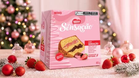 Panettone Nestlé Sensação com recheio duplo de morango e chocolate Embalagem do Panettone Nestlé Sensação com recheio duplo de morango e chocolate, ao lado de frutas e enfeites de Natal.