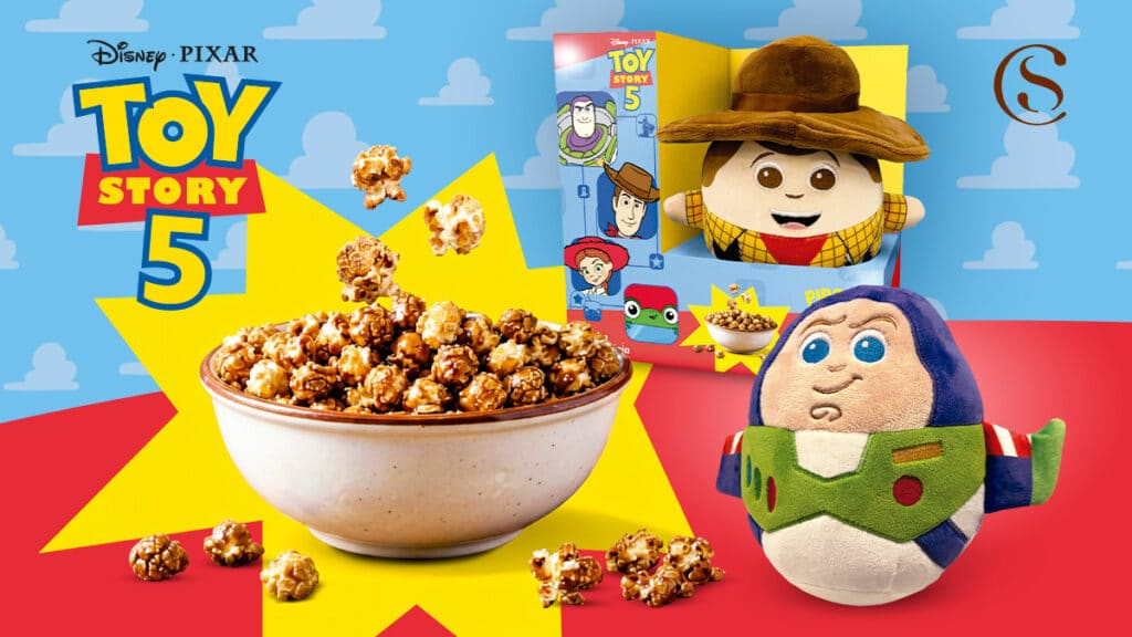 Pipoca Toy Story com pelúcias Buzz e Woody da Cacau Show Embalagem do Cacau Show com Pipoca Toy Story e pelúcias do Buzz e do Woody ao lado.