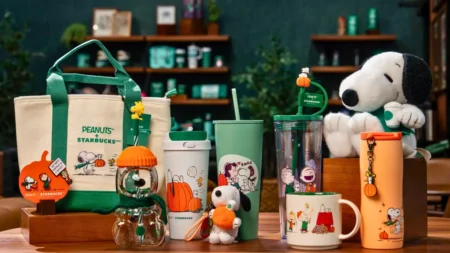 Coleção Starbucks Snoopy com Peanuts: itens e acessórios na mesa Coleção Starbucks Snoopy com itens exibidos em mesa, incluindo copos e sacola verde com personagens Peanuts.