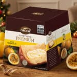 Embalagem de panetone Premium da Arcor sabor maracujá, com frutas e decoração natalina ao fundo.