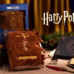 Embalagem e pelúcia interativa do Livro dos Monstros de Harry Potter em cenário de Natal da Cacau Show.
