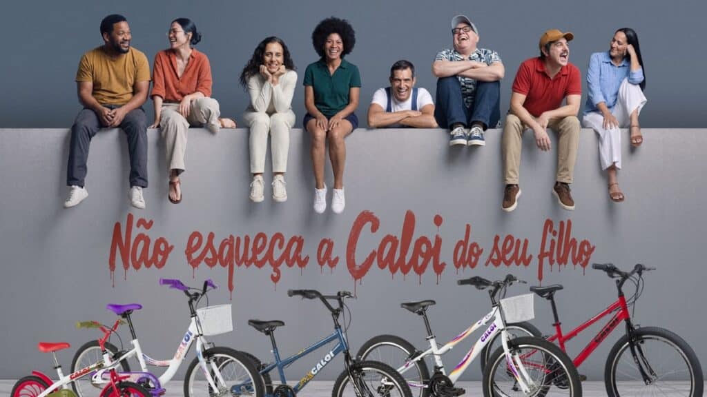 Família sentada com bicicletas ao fundo e texto “Não esqueça a Caloi do seu filho” em campanha da Caloi.