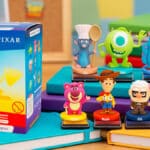 Blind box de carimbos Pixar com caixa e personagens como Woody, Sully e Remy sobre mesa