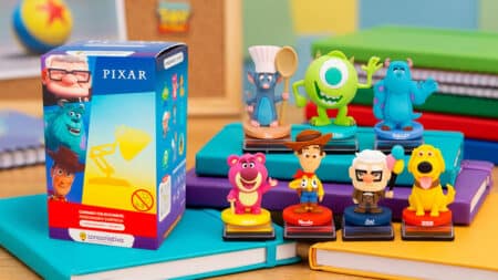 Blind Box de carimbos Pixar com personagens icônicos Blind box de carimbos Pixar com caixa e personagens como Woody, Sully e Remy sobre mesa