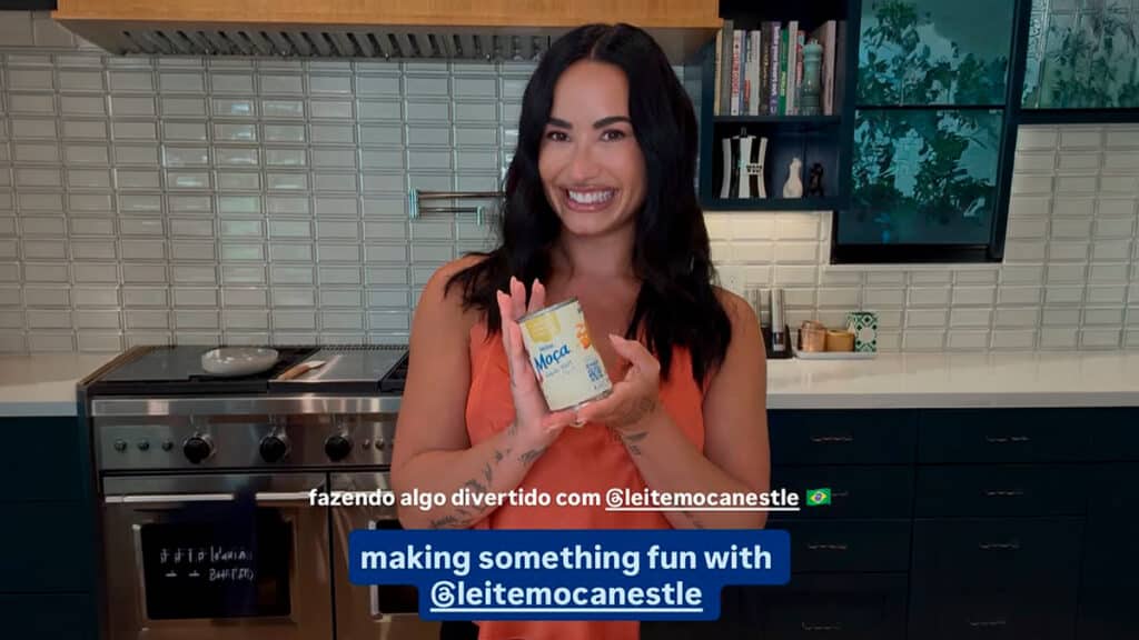 Receita com leite: inspiração em Demi Lovato Mulher sorri na cozinha, segurando uma embalagem de leite, em vídeo sobre receita inspirada em Demi Lovato