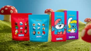Kopenhagen Smurfs: embalagens de chocolate com personagens Embalagens de chocolate Kopenhagen com tema Smurfs, com personagens dos Smurfs, sobre grama e cogumelos coloridos ao fundo.