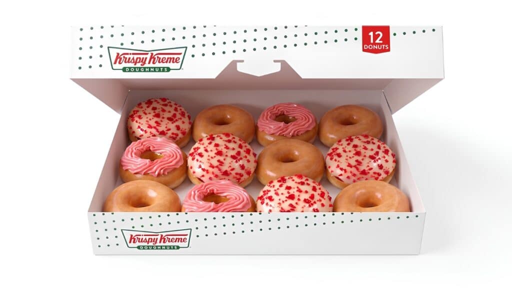 Caixa com 12 donuts da Krispy Kreme com cobertura de morango cravejado e creme rosa