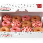Caixa com 12 donuts da Krispy Kreme com cobertura de morango cravejado e creme rosa